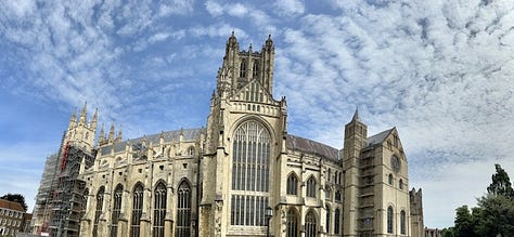 White woman poses awkwardly in front of cathedral and gardens