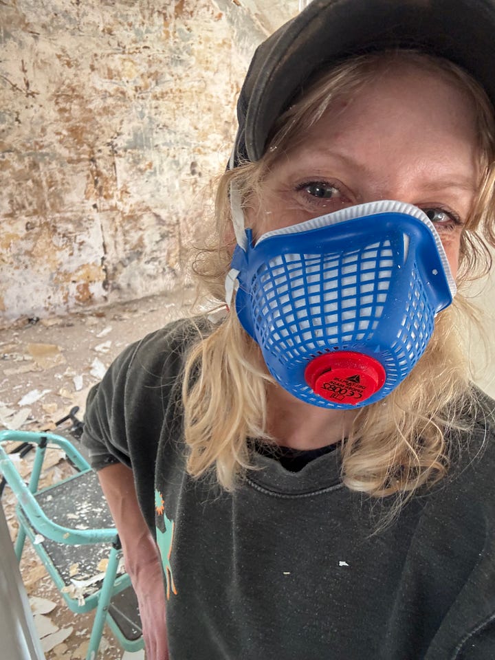 A photo of Gail wearing a dustmask standing in front of a wall where the wallpaper has been removed, and a photograph of old wooden floorboards that have been revealed in the upstairs hallway after she tore up the carpet. 