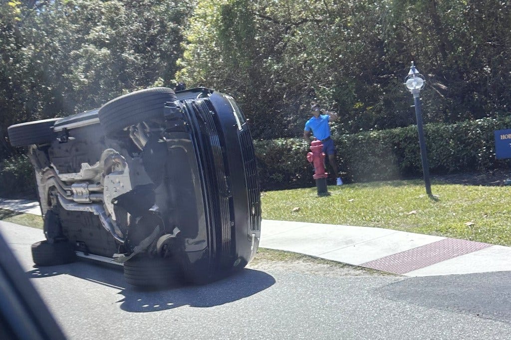 Tiger Woods standing by his overturned vehicle after a crash.
