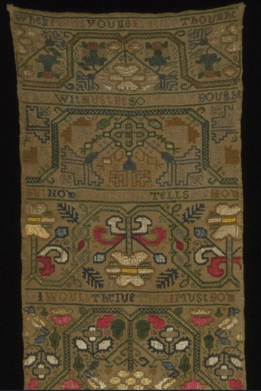 Sampler: embroidery on yellowed fabric. Lines of text are alternated with bars of nature inspired folk designs