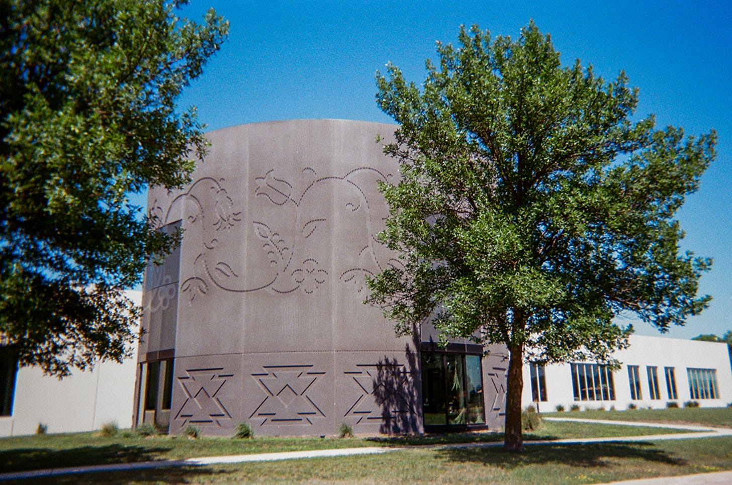 A debossed floral pattern draws attention to the circular black section of an otherwise white rectangular building.