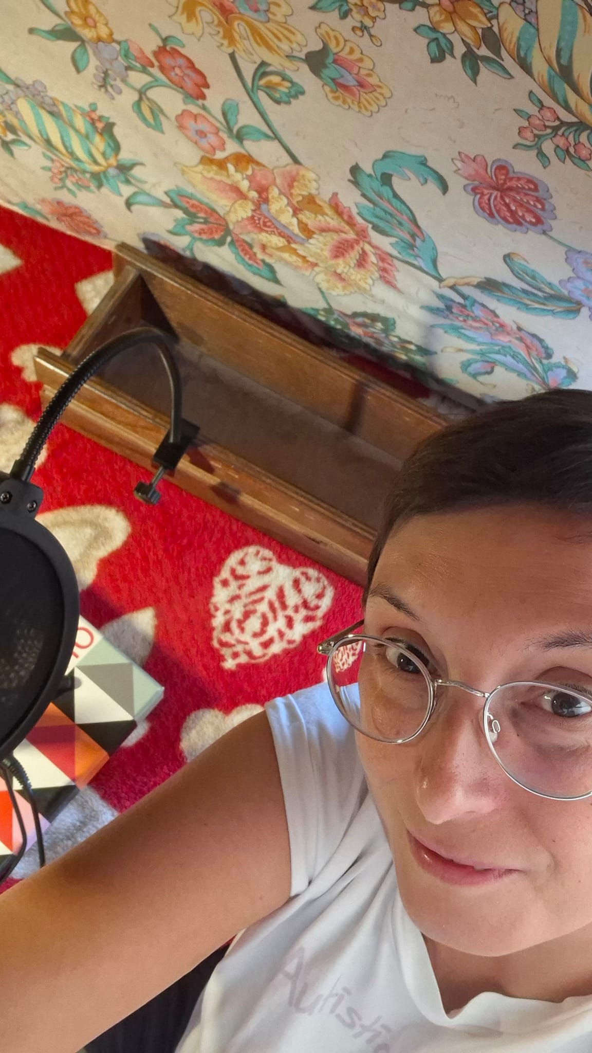 Selfie di me nella capanna. Si vedono il plaid rosso, il pop-filter fissato al cassetto, la scatola di un gioco di società e il materasso.