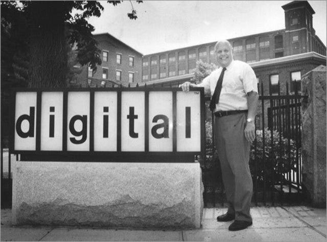 Kenneth "Ken" Olsen, co-founder of Digital Equipment Corporation, standing next to the Main Street sign.