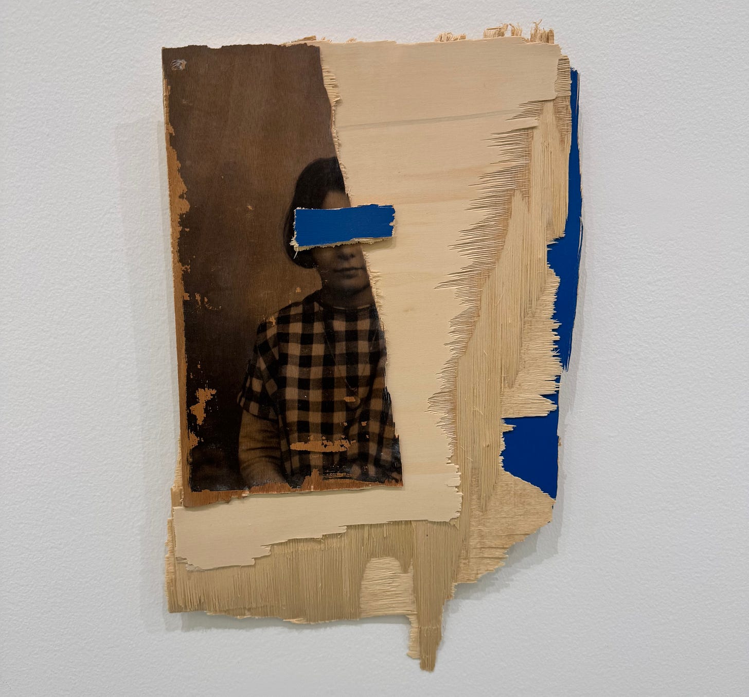 A photograph of a woman, torn in half with paper covering her eyes, mounted on a small piece of wood. A photograph of a woman, torn in half with paper covering her eyes, mounted on a small piece of wood.