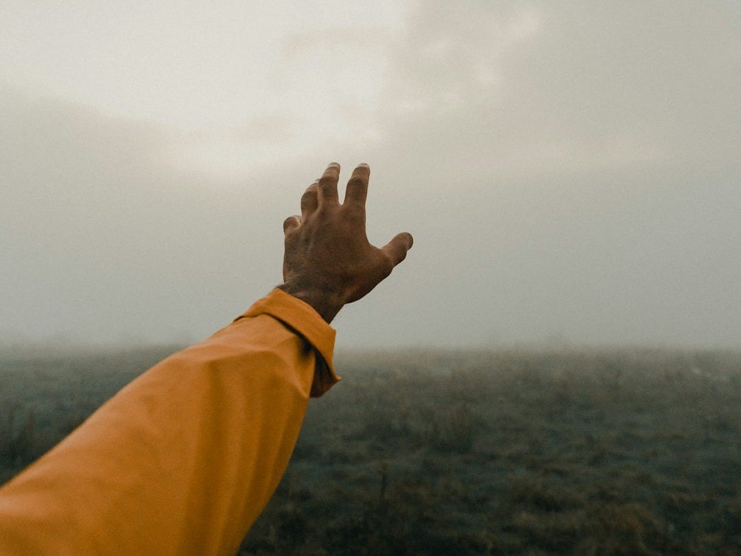 person in yellow long sleeve shirt raising right hand