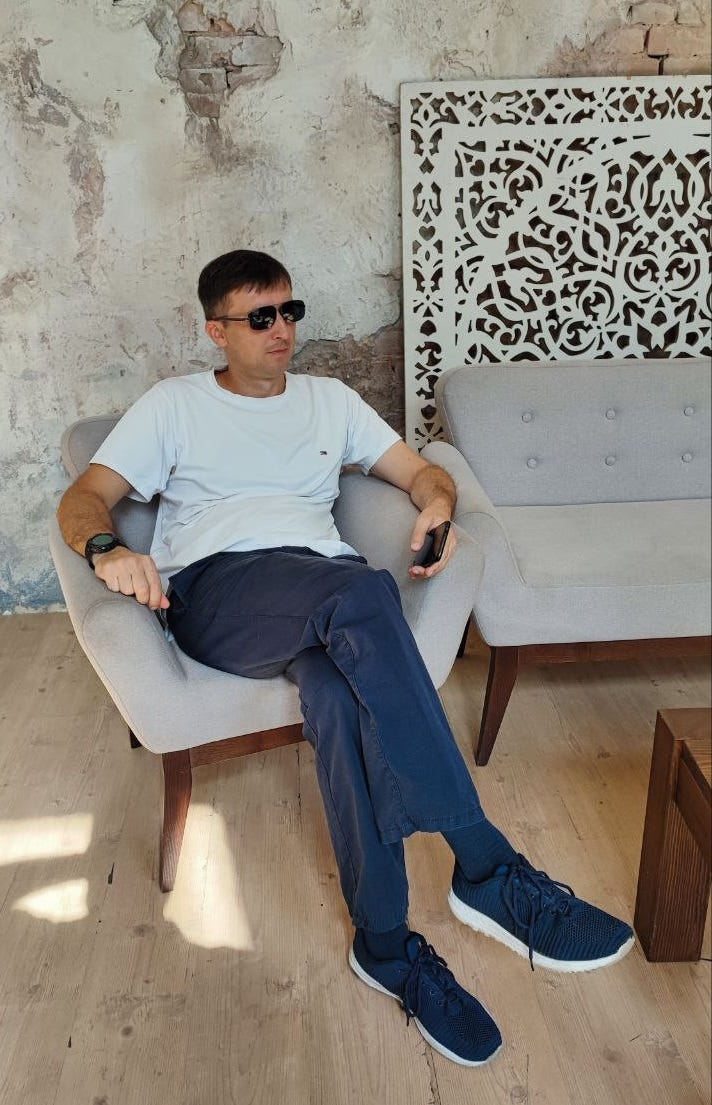 A man in sunglasses sits in t-shirt and jeans holding a phone. A man in sunglasses sits in t-shirt and jeans holding a phone.