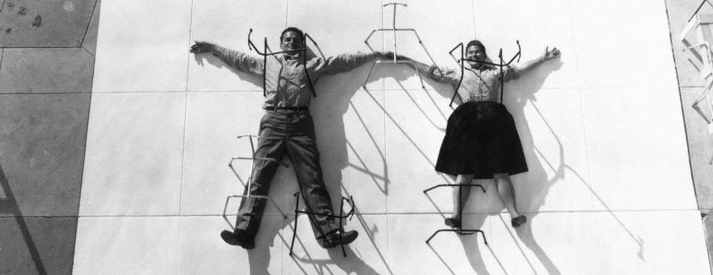 Charles and Ray Eams posing with the tubular structure of their chairs