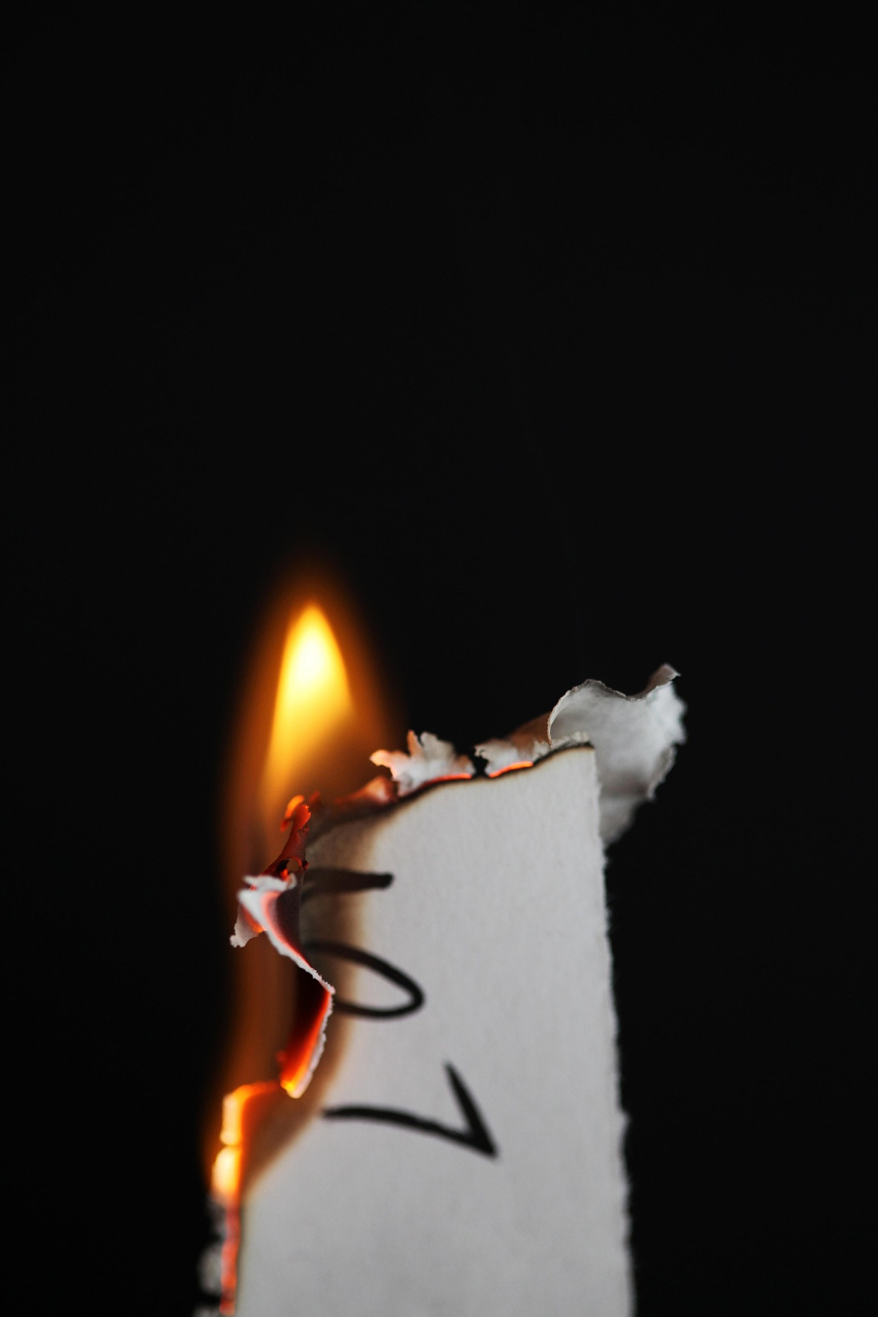 A corner of a letter that is on fire, on a black background.