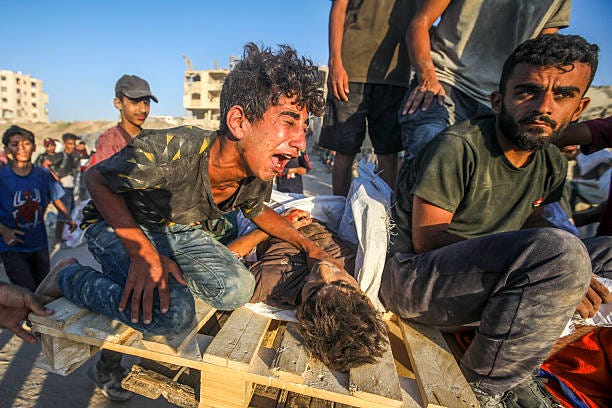 Displaced Palestinians at the Nuseirat refugee camp haul food parcels and other items they manage to retrieve from a Gaza Humanitarian Foundation aid...