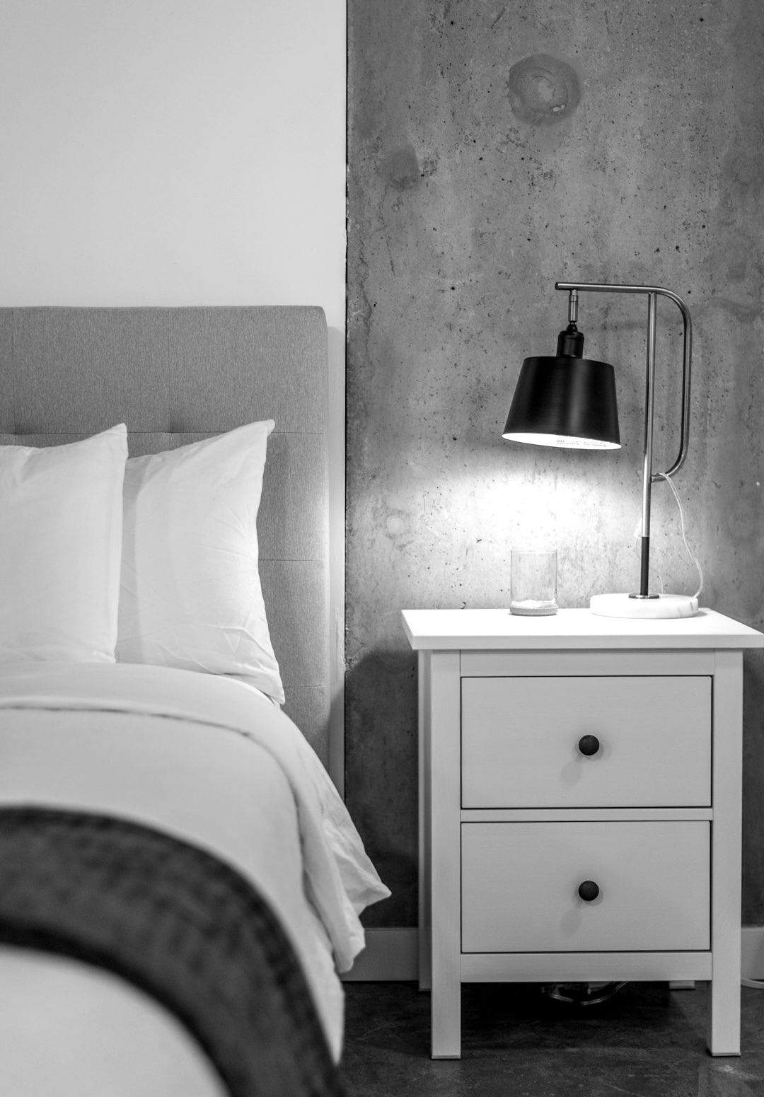 a bedroom with a bed, nightstand, and lamp
