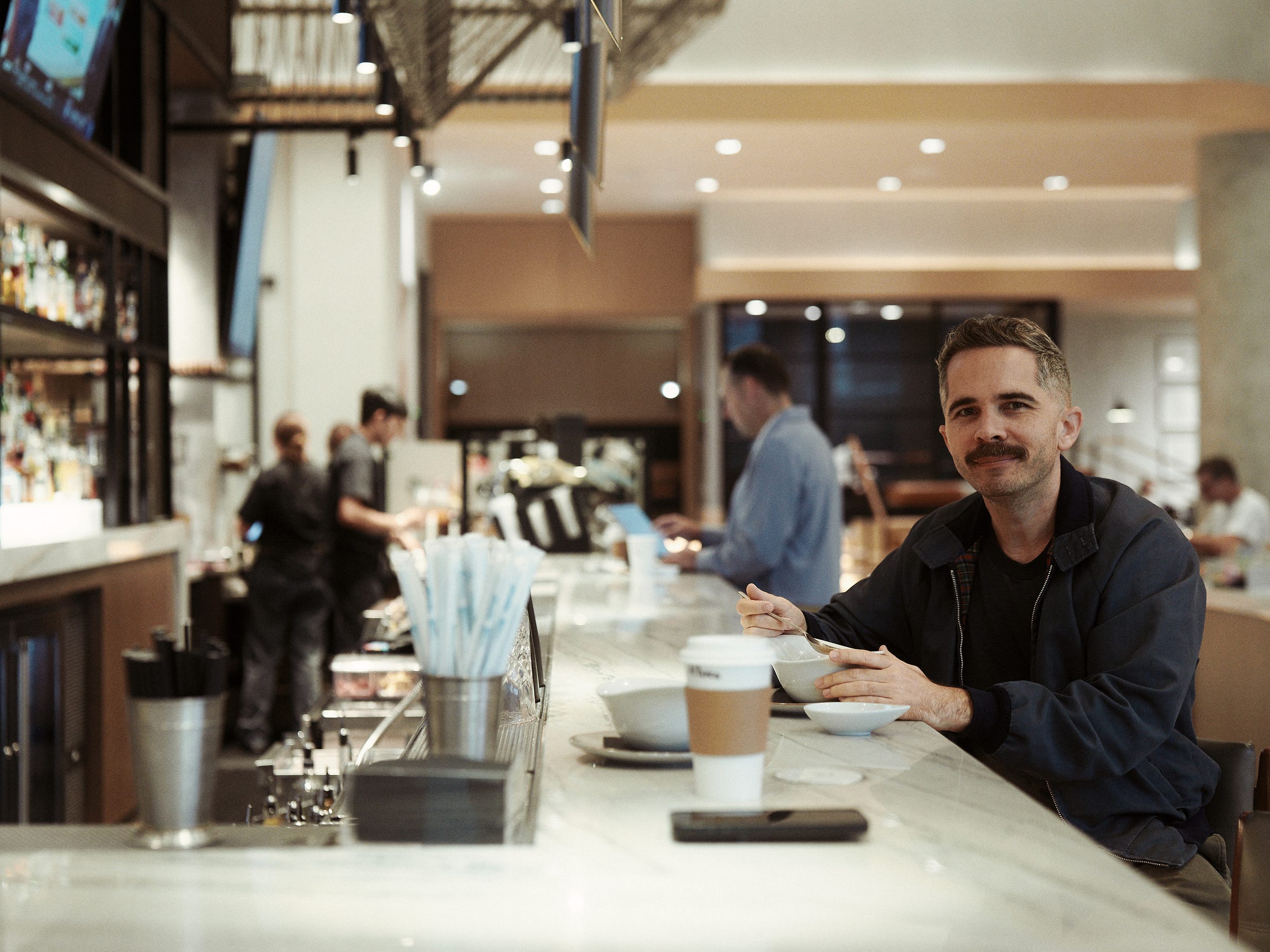 A smiling man eats breakfast sitting at the counter in the hotel lobby in Phoenix, Arizona, taken by LA photographer Afonso Salcedo