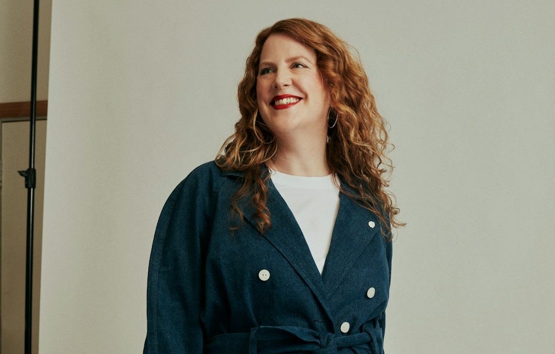 a woman standing in front of a mirror wearing a blue coat