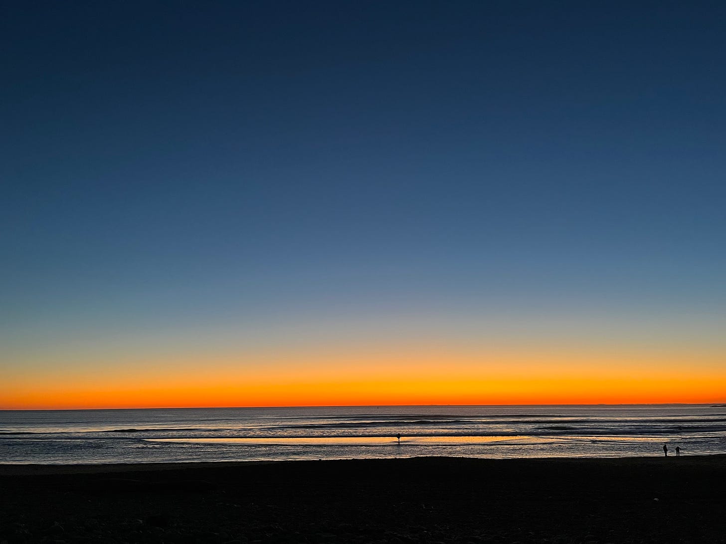 Dark blue sky with dark orange band on the horizon, from the beach.