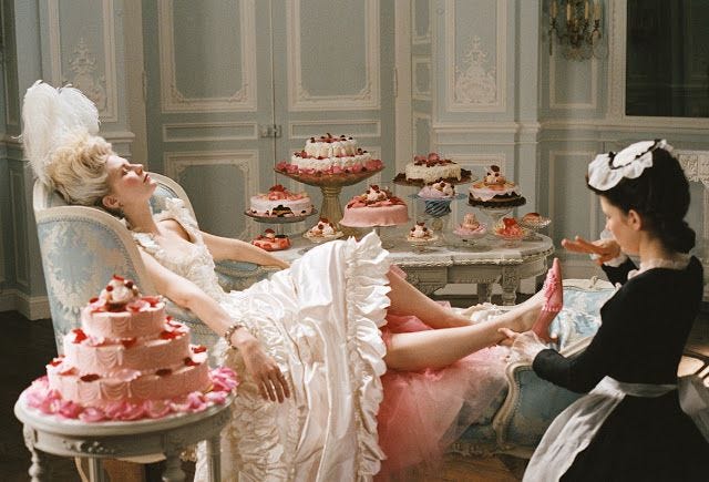 This may contain: a woman laying on a chair next to a table filled with cakes