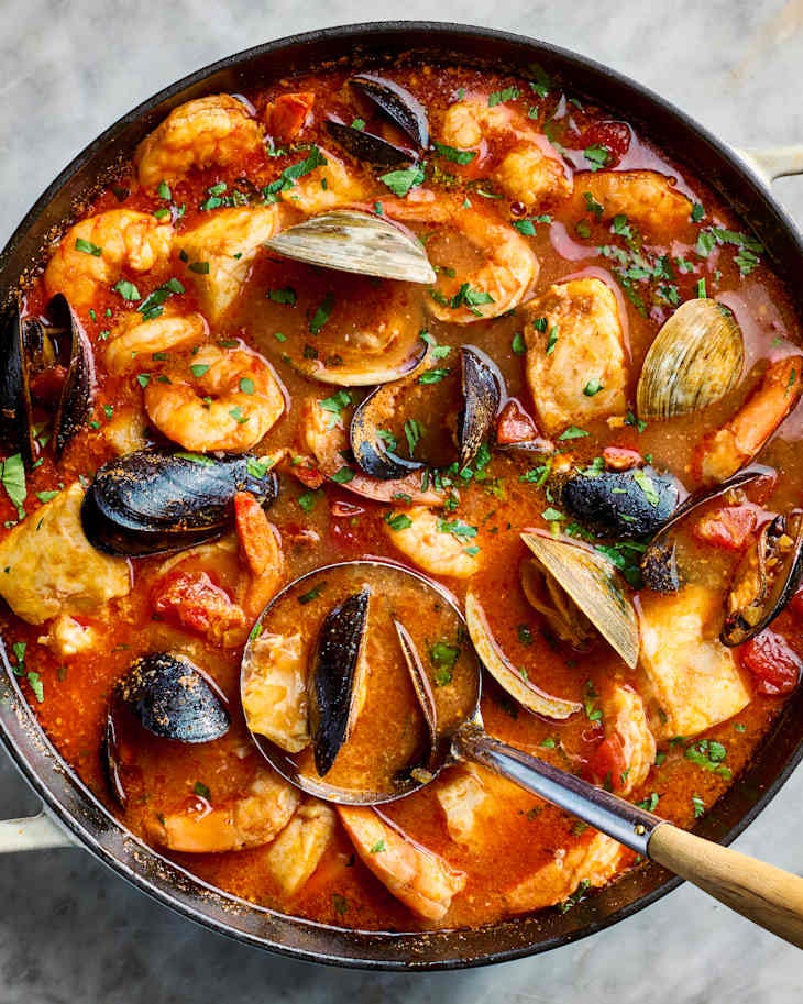 overhead shot of cioppino in a pot, topped with herbs