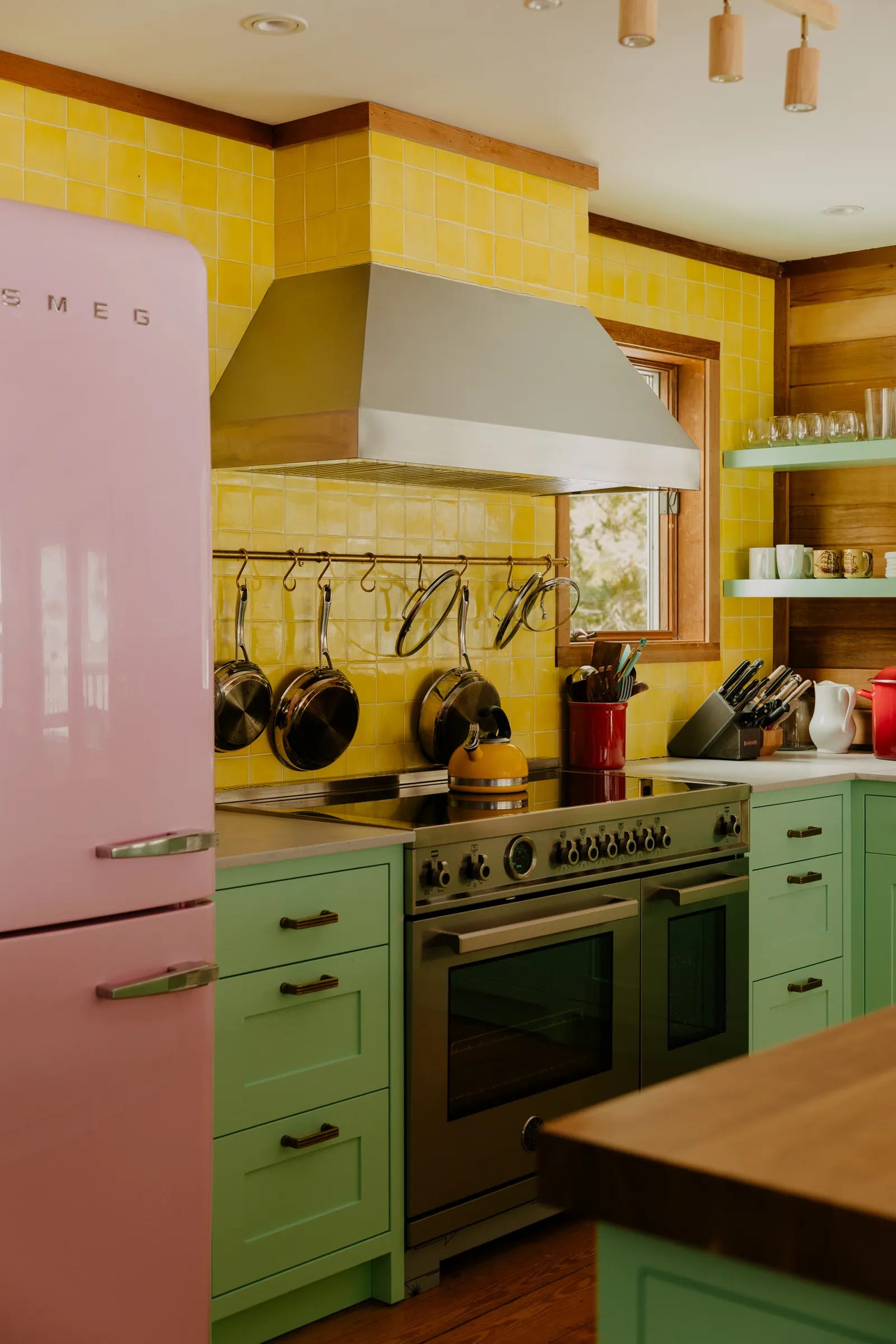 Yellow kitchen tiles, a pink refrigerator, and mint green cabinets