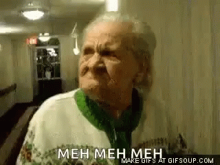 an elderly woman is making a funny face in a hallway while wearing a green sweater .