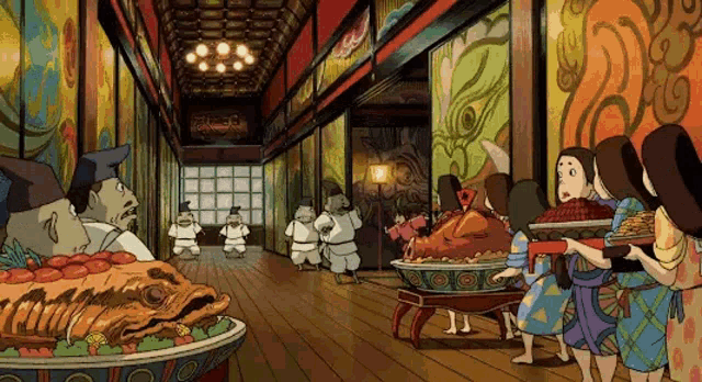 a group of people standing around a large bowl of food in a hallway . a group of people standing around a large bowl of food in a hallway .