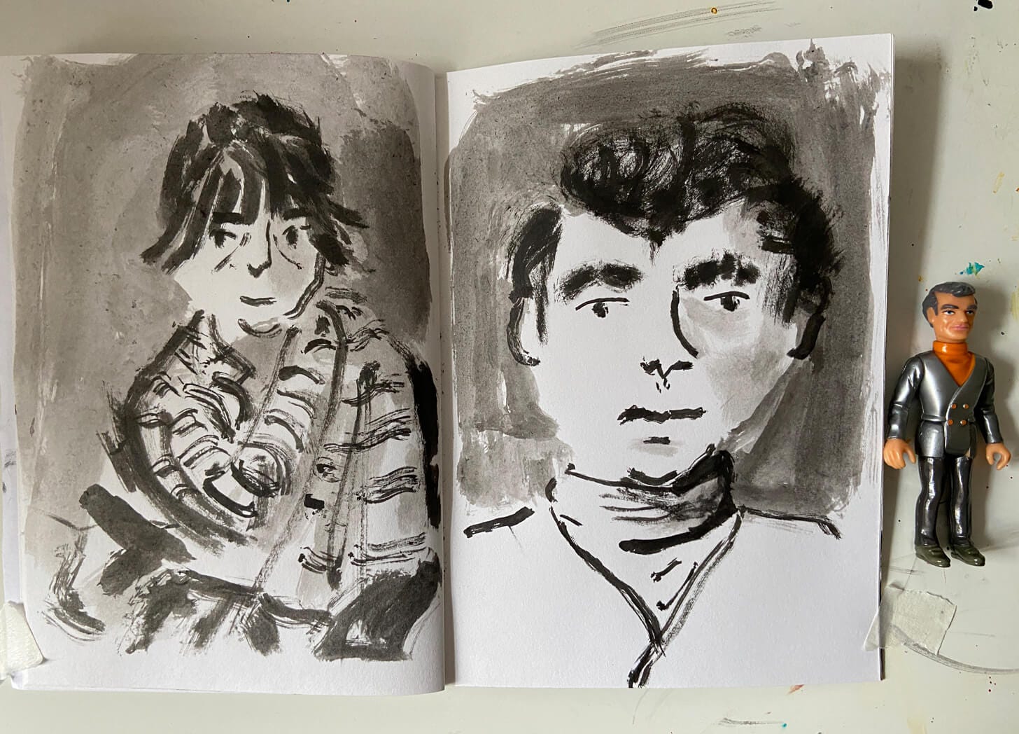Sketchbook of textured loose drawings in ink by Nanette Regan. Next to toy figure. Sketchbook of textured loose drawings in ink by Nanette Regan. Next to toy figure.