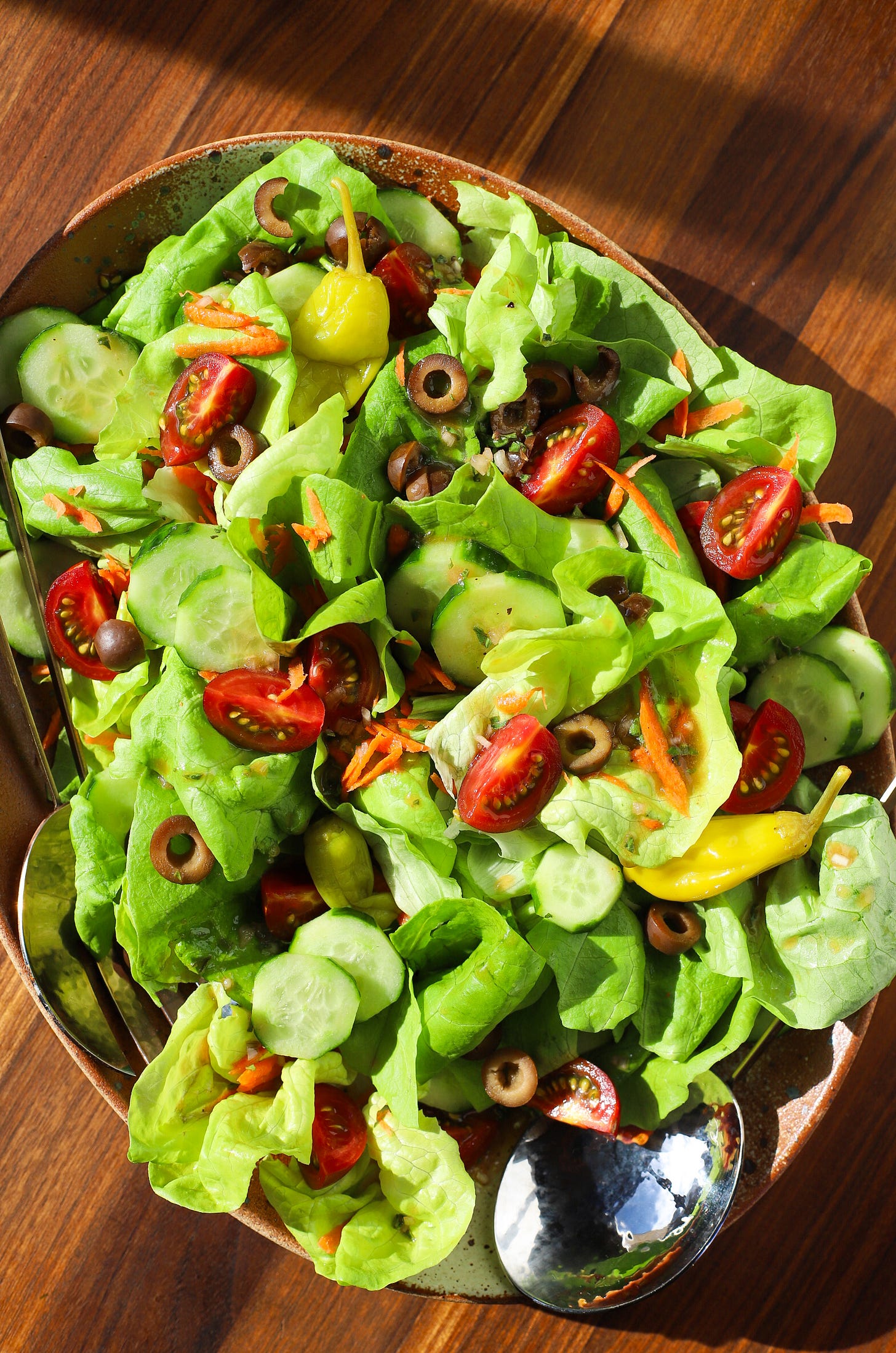 Platter with lettuce, tomatoes, cucumbers, black olives, and pepperoncini