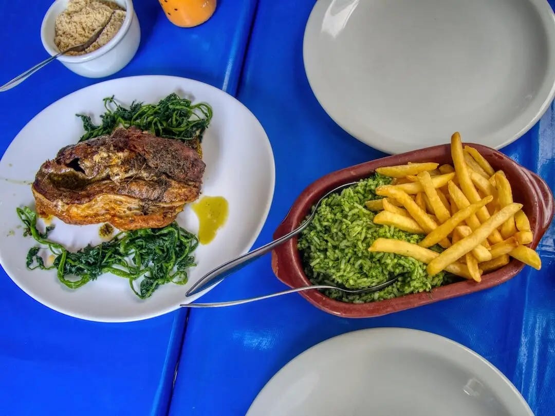 Separate plates of meat, green rice and fries