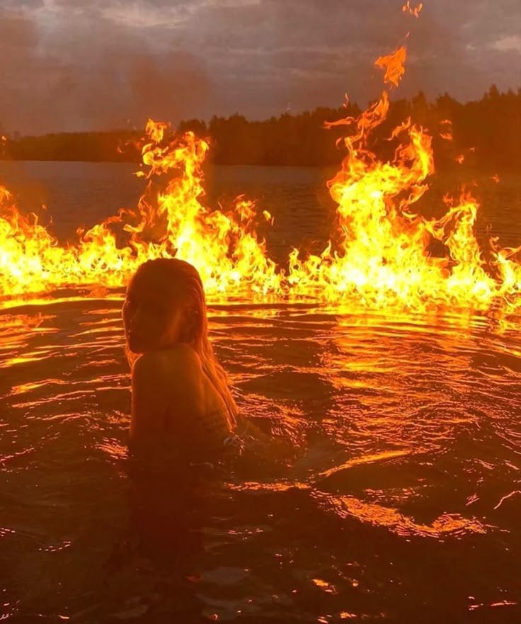 This may contain: a woman in the water with fire coming out of her face