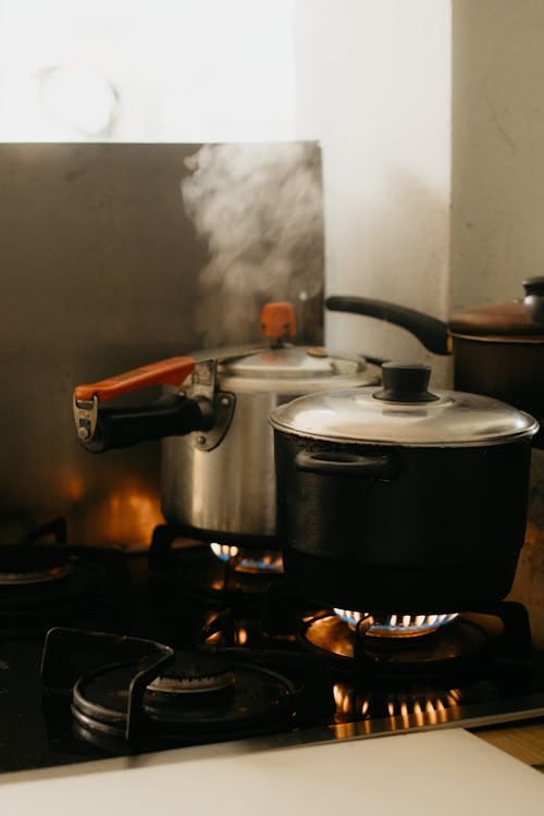 Free Steaming pots on a kitchen stove with smoke rising in a cozy indoor setting. Stock Photo