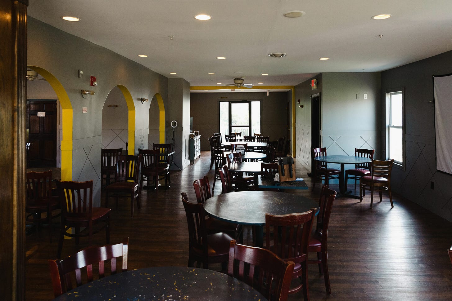 a second-floor dining space with a large projector screen