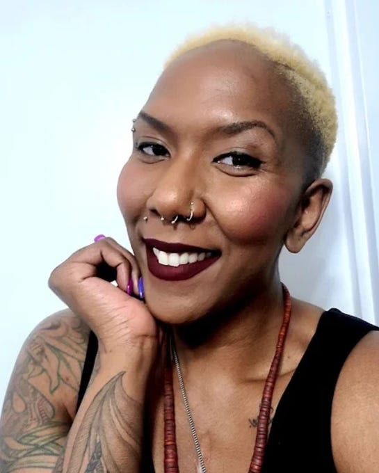 First image shows a woman with short blonde hair smiling at the camera with purple lipstick nose ring lip piercings tattoos on her arm wearing a black top and beaded necklace against a white background. Second image depicts a person with long blonde hair wearing dark clothing leaning head down on a open white padded wooden casket in a room with white walls lamps and gold stand.
