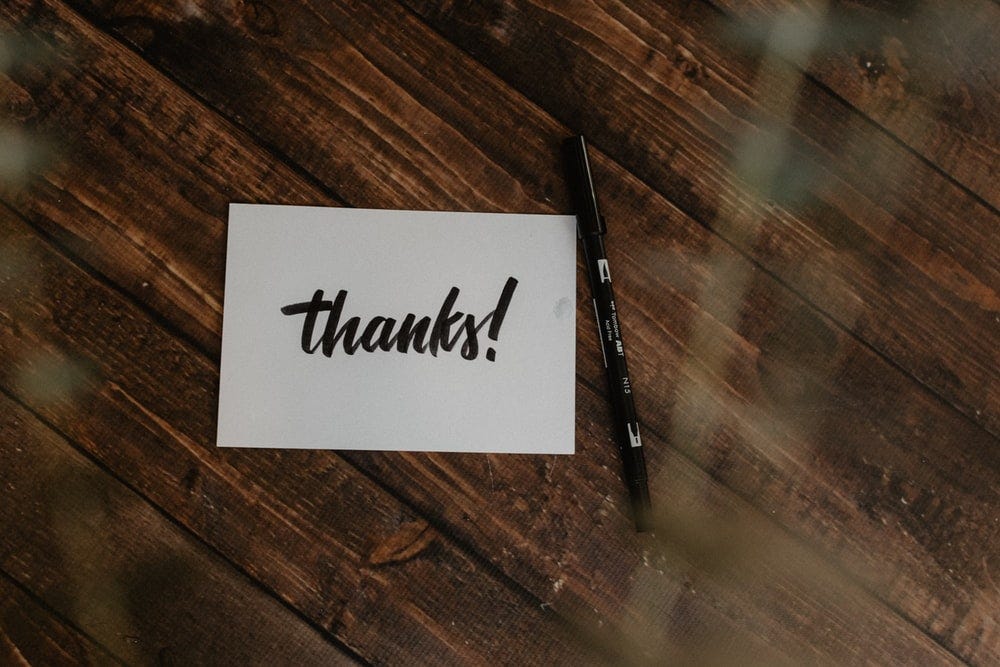 thanks! paper and black pen on wood surface thanks! paper and black pen on wood surface