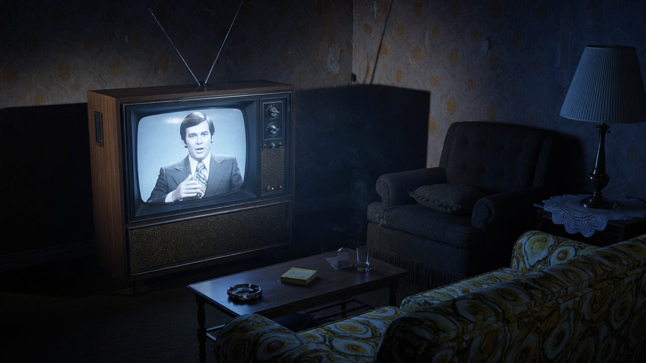 Vintage 1970s television as room’s only light source, suited figure visible on screen, dark living room with long shadows