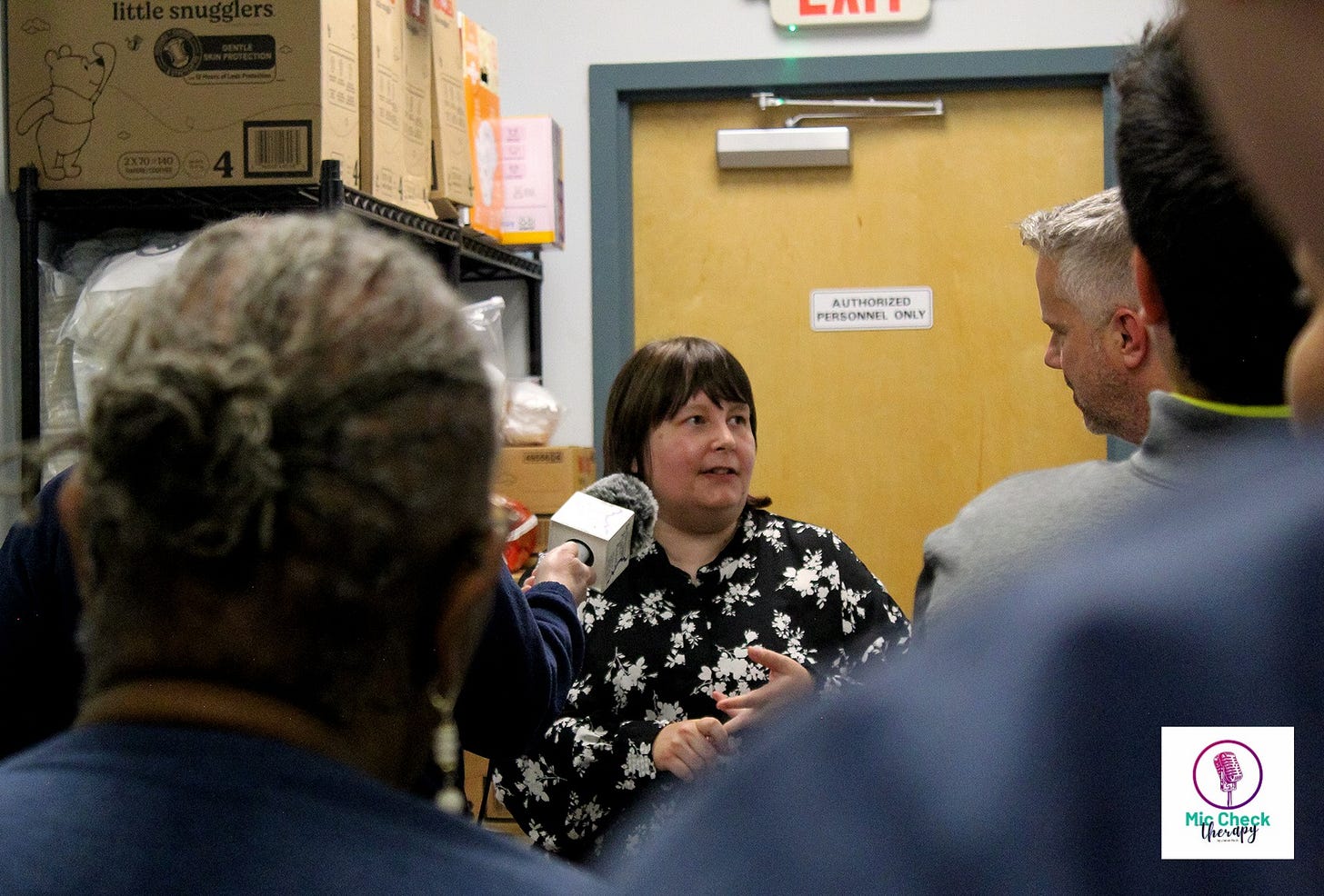 Jamie Roth standing in front of a group of reporters. A microphone records what she is saying as she speaks with a Congressman.
