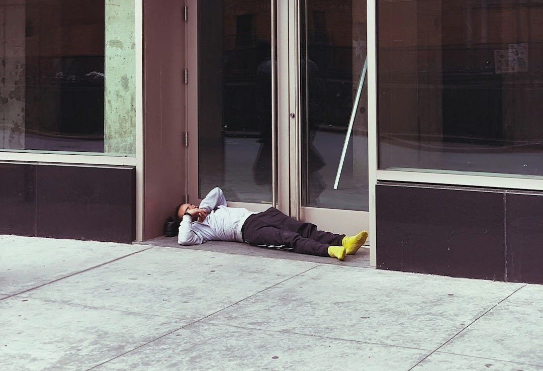 person laying beside black and white building during daytime