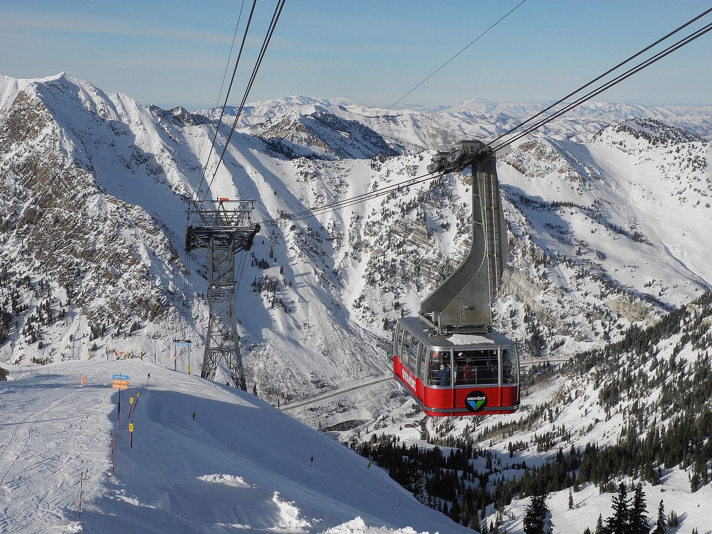 Red Snowbird tram car nearing the Hidden Peak station above snowy Wasatch ridges