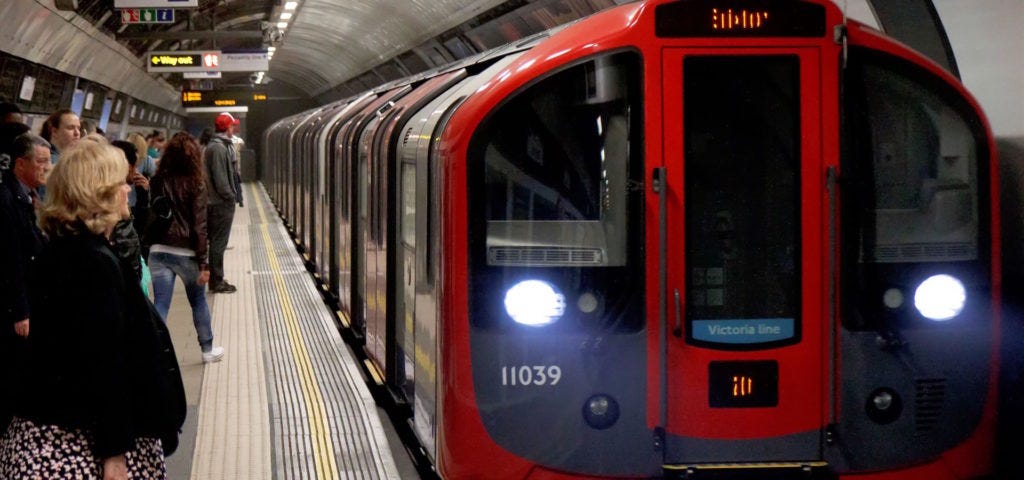 passengers wait to get into a train pulling into a London underground station.