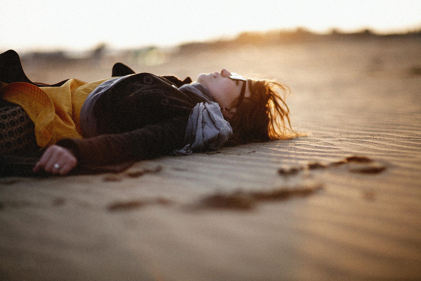 Woman lying on a sandy beach at sunset Woman lying on a sandy beach at sunset