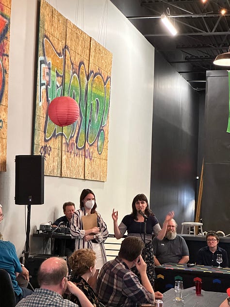 Five photos show various scenes at a party with people wearing flannels and tee shirts sitting down at tables, and people standing up at a microphone, and a panel of people sitting, one person speaking into a microphone. The last photo shows 7 people holding a yellow banner reading in black text: "Labor Education Service"