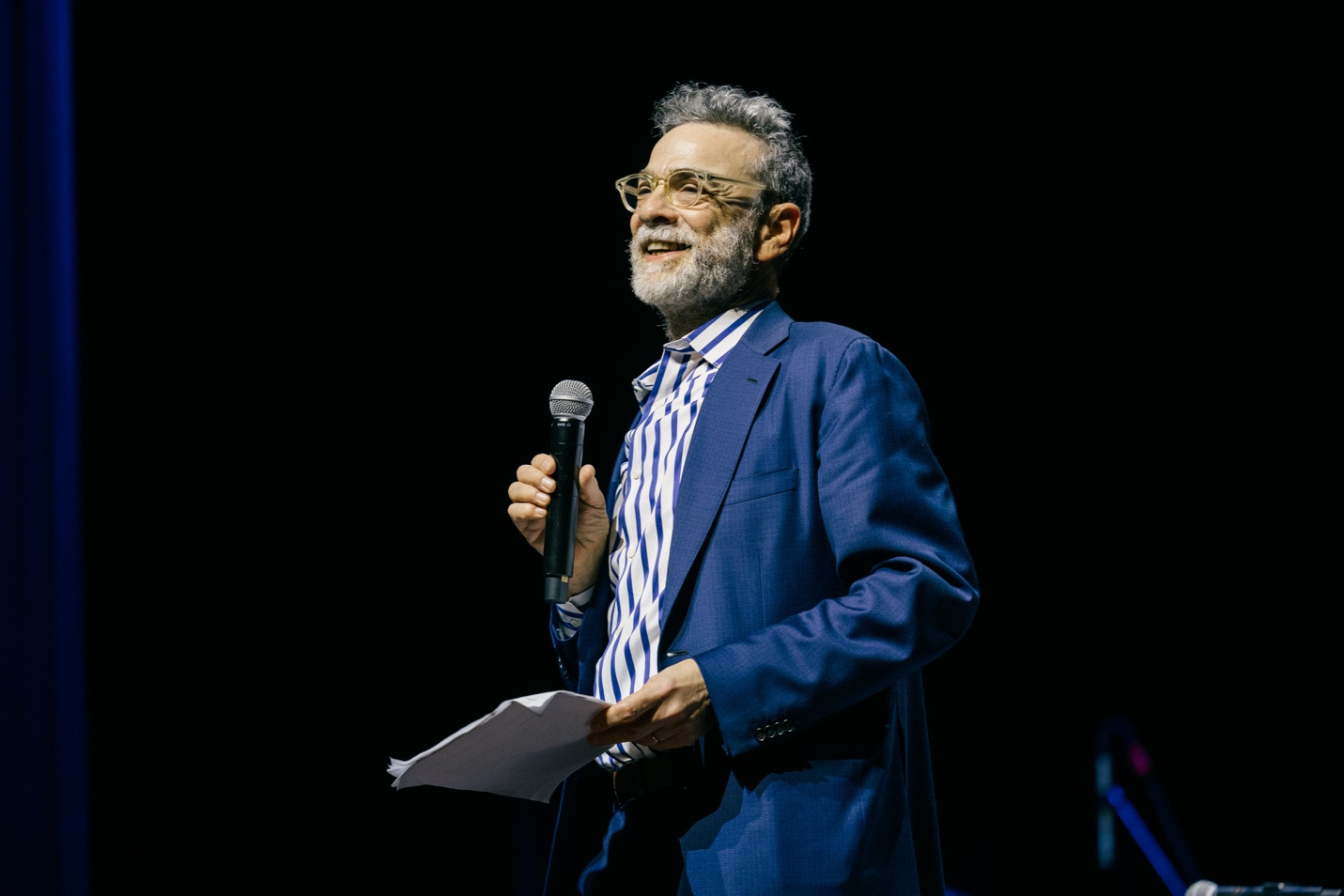A person in a suit holding a microphone

Description automatically generated