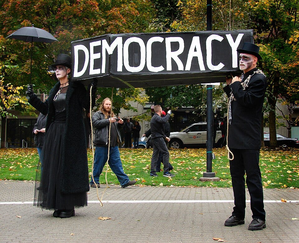 Protestors dressed in gothic style funeral wear carry a coffin labeled, "Democracy" in Portland, OR protests.