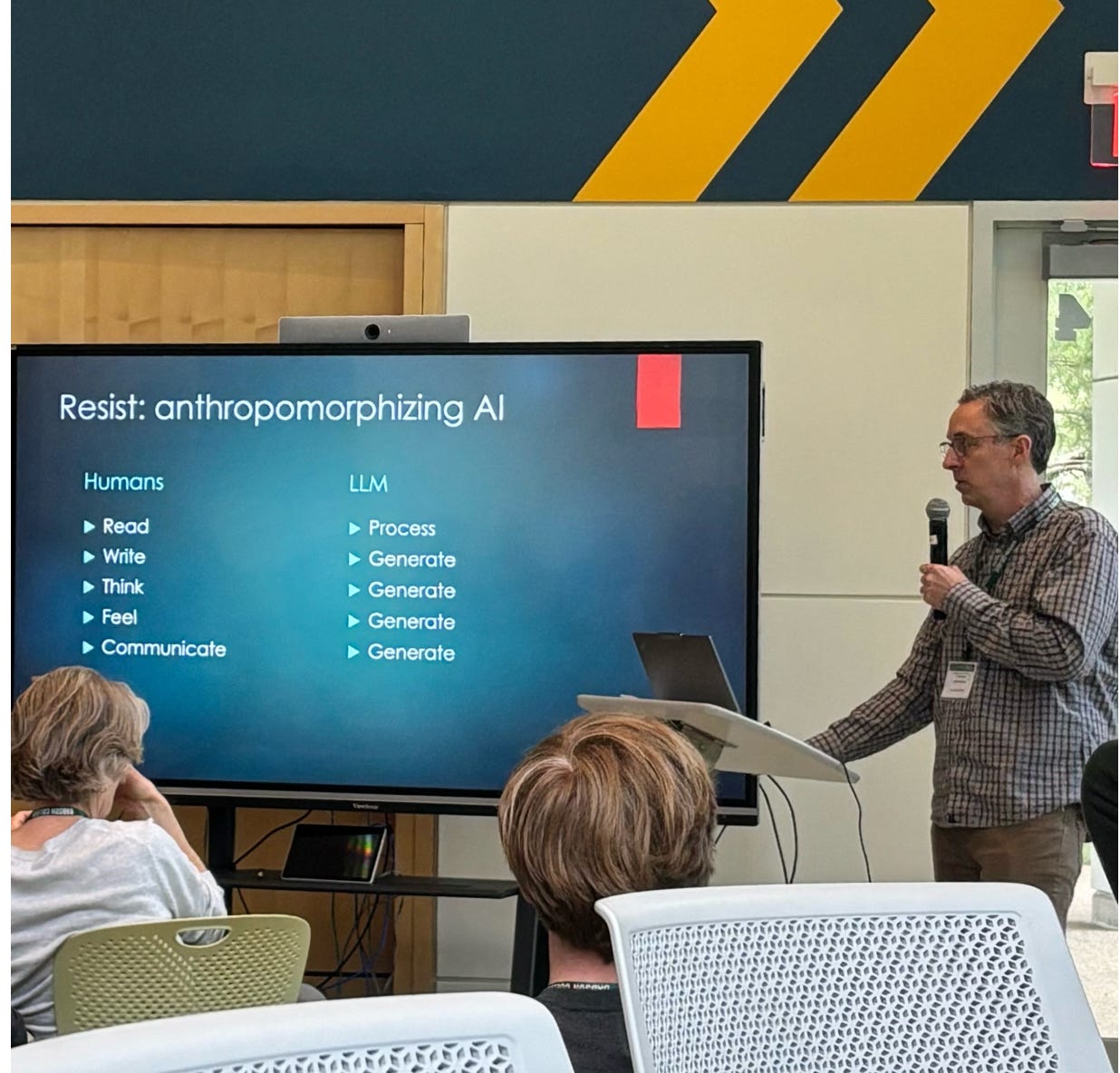 Man standing next to a screen. On the screen is a list of human activites: read, write, think, feel, communicate. On the other side of the screen are AI activities. For every human activity, the AI side just says"generate." The heading is "Resist anthropomorphizing AI"