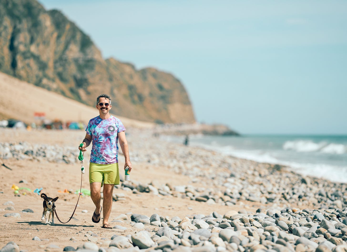 A man walks his chihuahua on a leash at Thornhill Broome Beach near Malibu, California