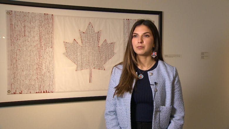 A woman standing in front of a white impression of the Canadian flag.
