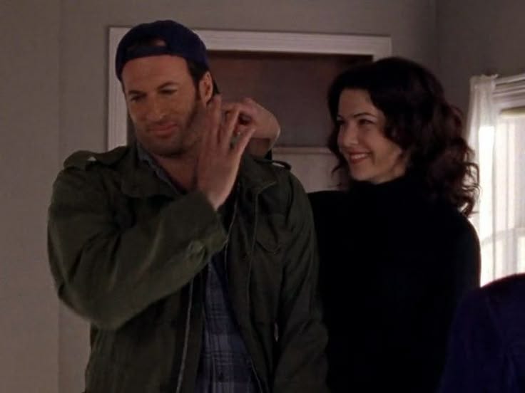 This may contain: a man standing next to a woman in a room with a door and window behind him