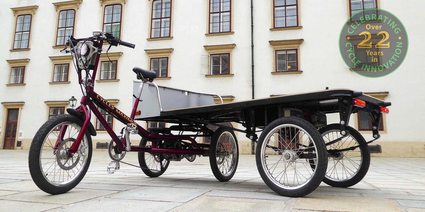 A brand new tricycle and trailer are shown on a paved city street. 
