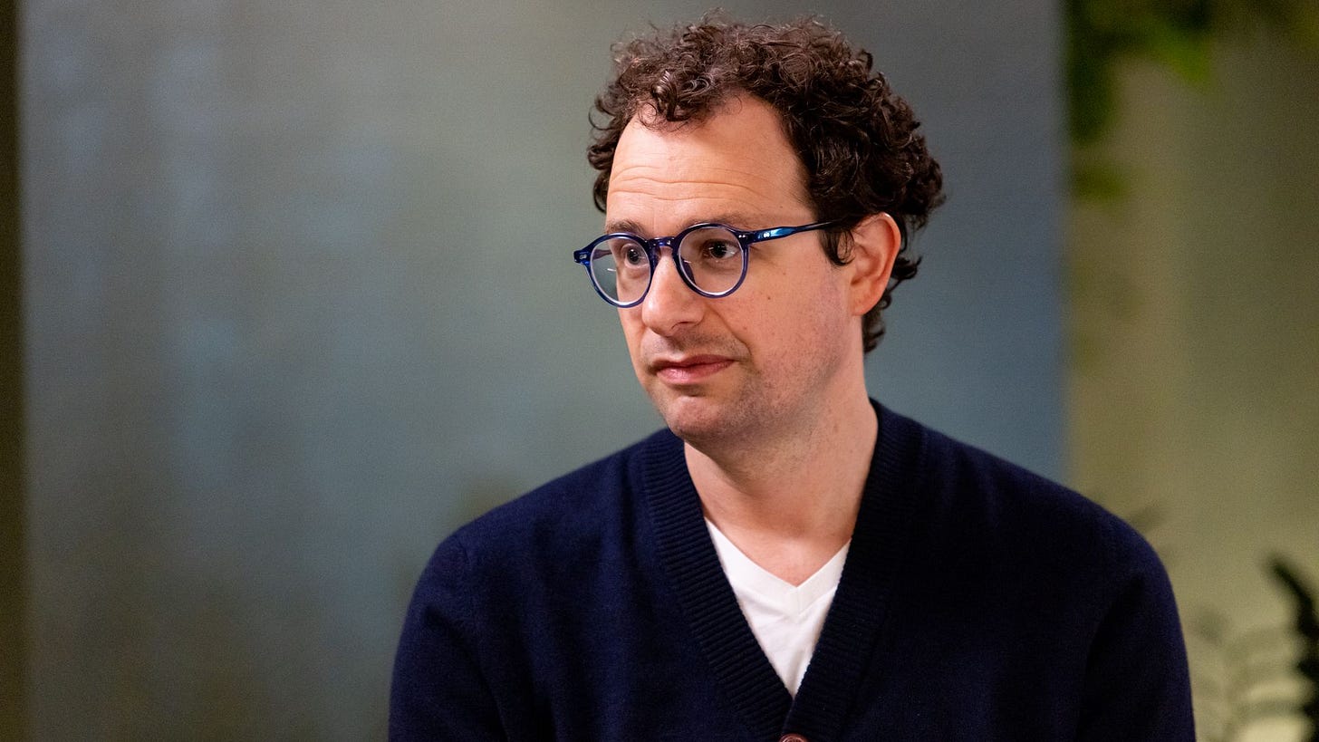 Anthropic CEO Dario Amodei, seated in front of a blurry gray background. 