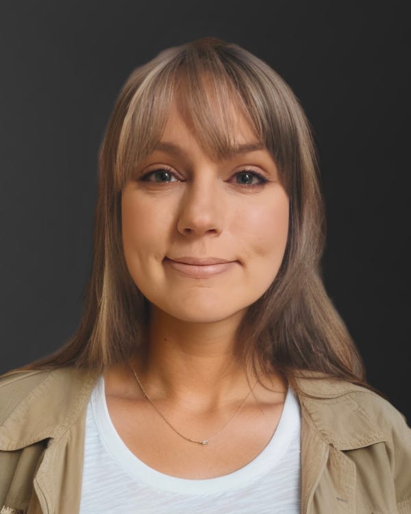 Picture of Kyle Soucy. She has long light brown hair with some gray streaks and she's wearing a white t-shirt with a khaki collared shirt.