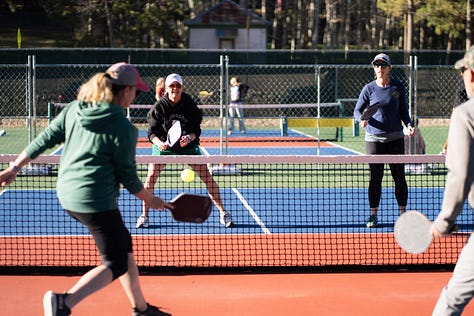 six pickleball courts, players in position, holding their paddles 