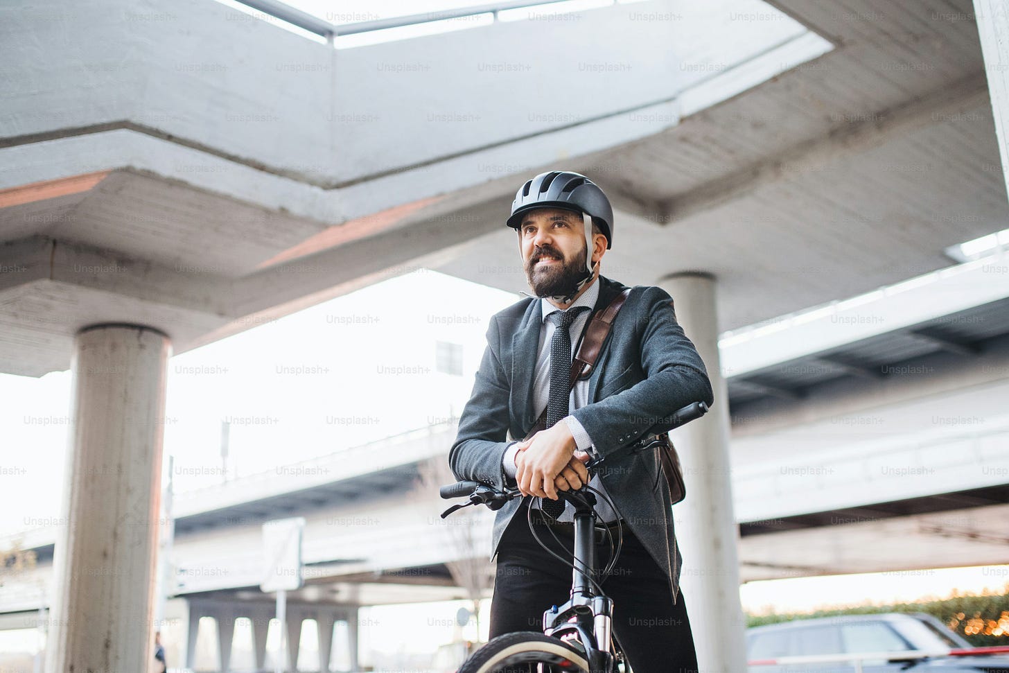 Hipster businessman commuter with bicycle on the way to work in city,  standing and using smartphone. photo – City Image on Unsplash