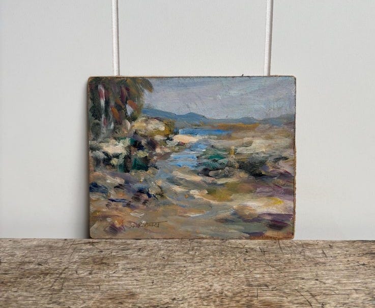 May include: An oil painting on a rectangular board depicting a landscape with a stream, earthy tones, and visible brushstrokes. The scene features muted blues, browns, and greens, with a signature in the bottom left corner. The artwork is presented on a flat surface.