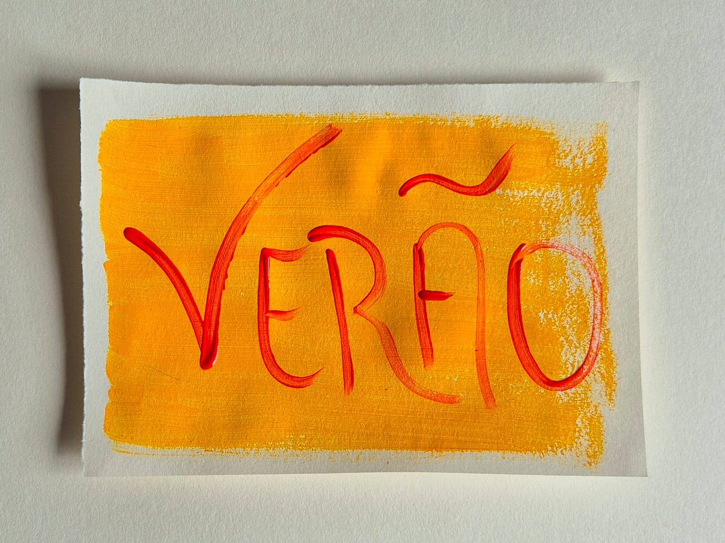 Fotografia de um papel pintado de amarelo com a palavra Verão escrita em vermelho